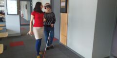 Uczestnik szkolenia idzie z białą laską i zasłoniętymi oczami