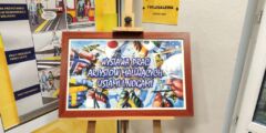 Tablica stojąca przed Tyflogalerią PZN z napisem: Wystawa Prac Artystów Malujących Ustami.