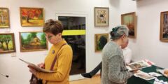 Galeria. Dwie kobiety odwrócone do siebie plecami. Każda w dłoniach trzyma papierową reprodukcję obrazu.
