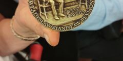 Kobieta trzyma w ręku medal okolicznościowy