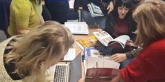 Uczestnicy szkolenia przeglądają stronę na laptopie oraz materiały drukowane.